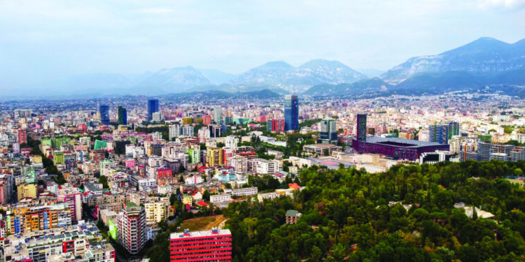 Aerial drone view of Tirana, Albania. City centre with modern buildings, stadium, residential district and greenery. Mountains in the distance